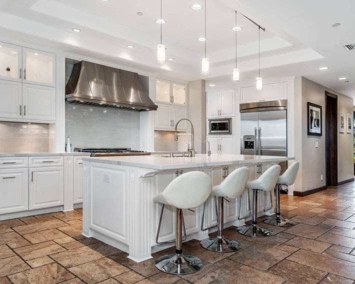 A modern kitchen with four bar counters and stools
