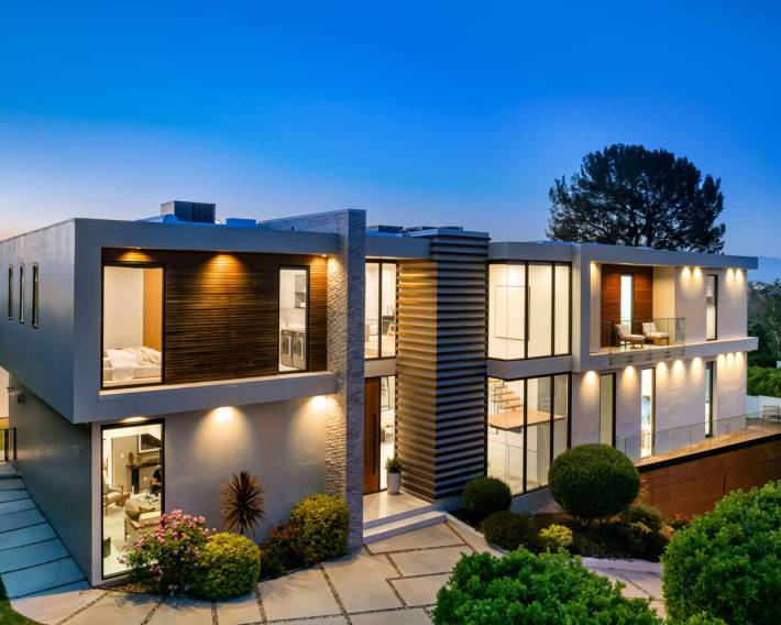A contemporary house with city lights visible from the balcony